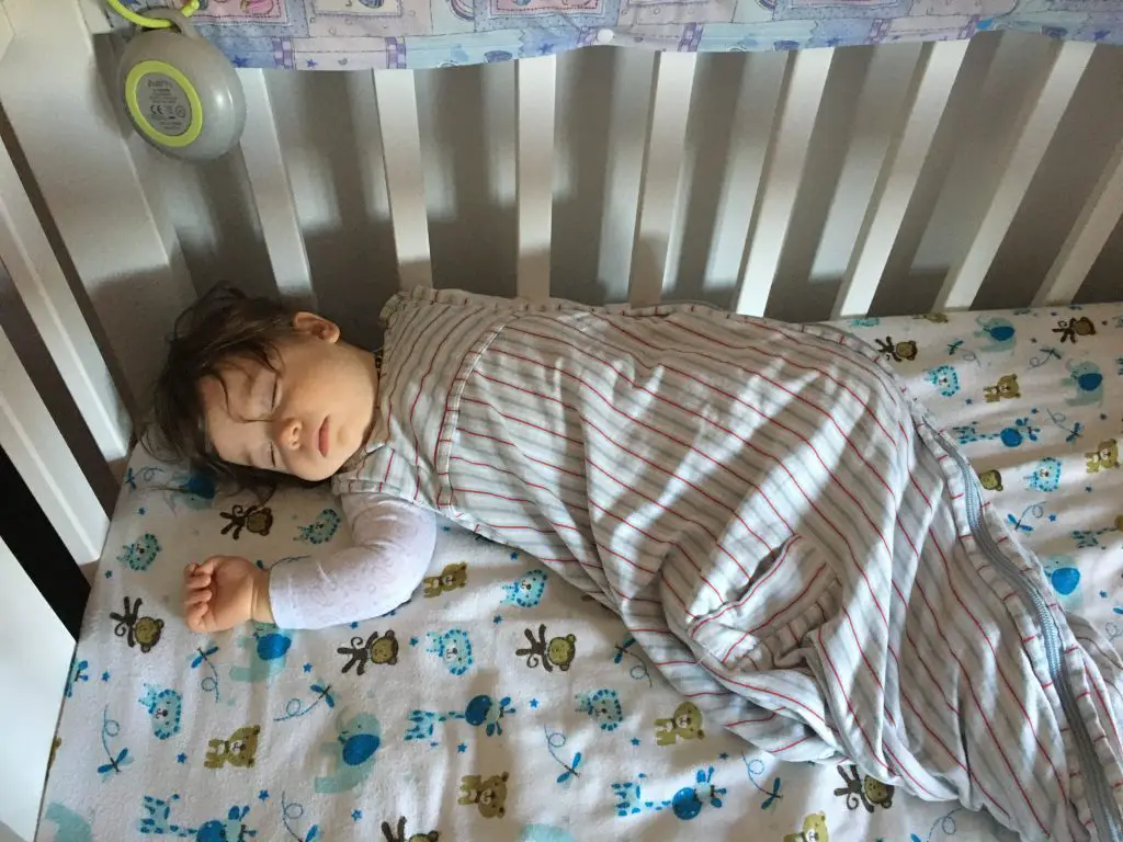 baby sleeping in crib with sleeping bag